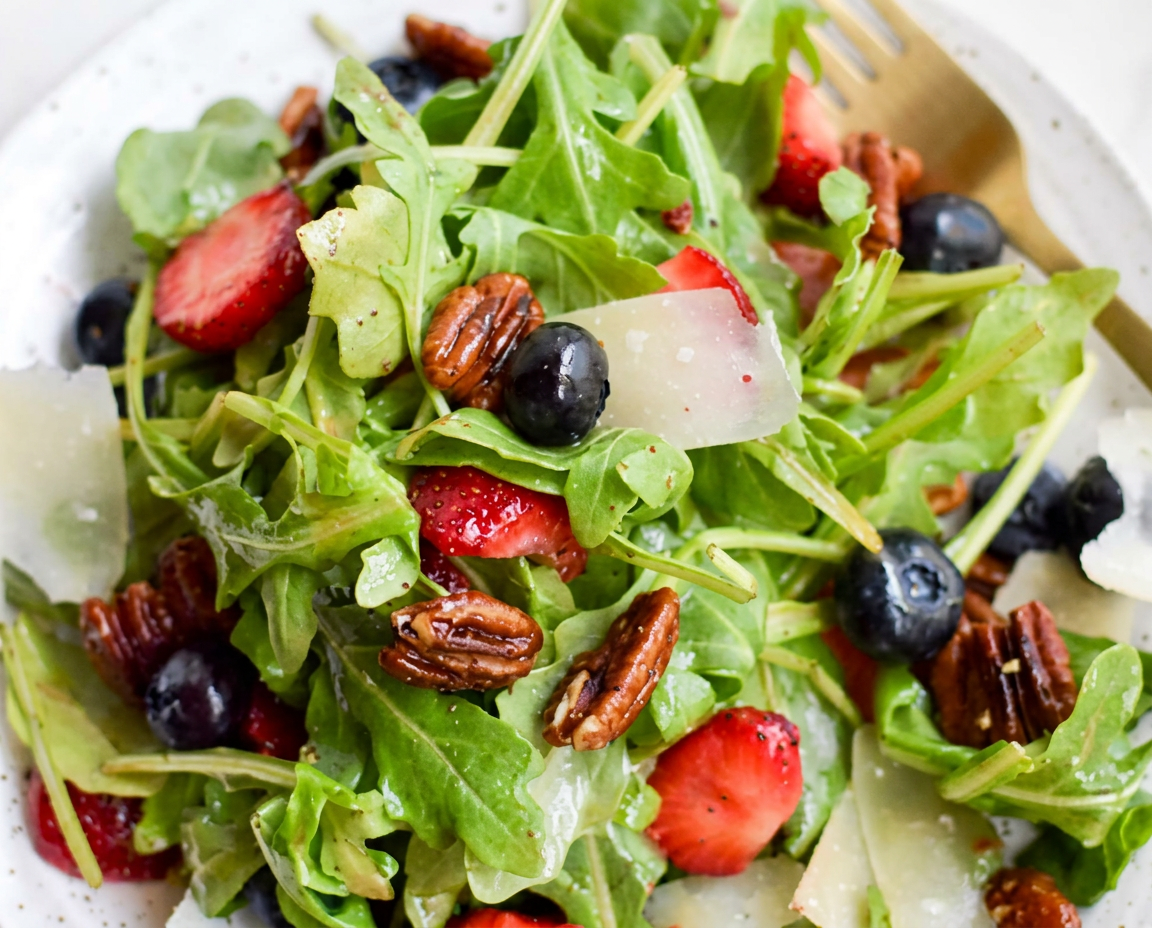 Salade fraîche de roquette, fruits rouges et copeaux de fromage